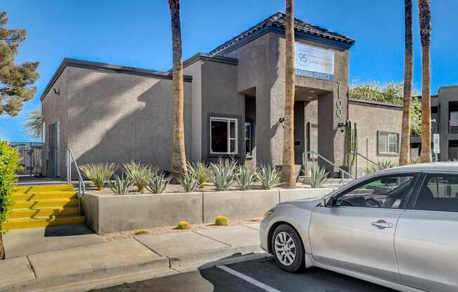 A silver car is parked in front of a building with a sign that reads "95".