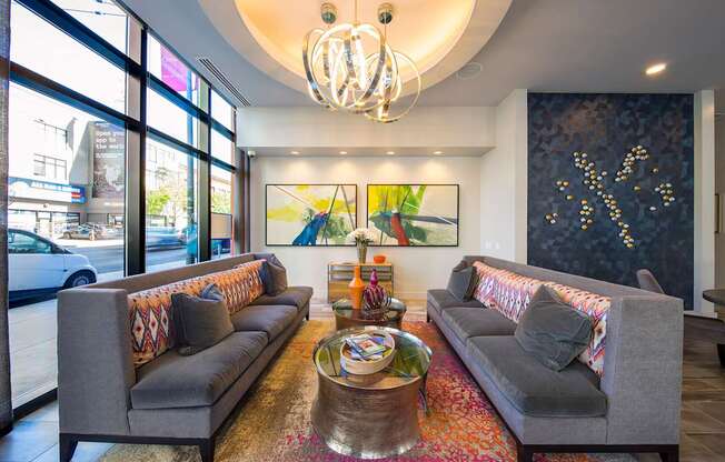 A living room with two grey couches, a coffee table, and a chandelier.