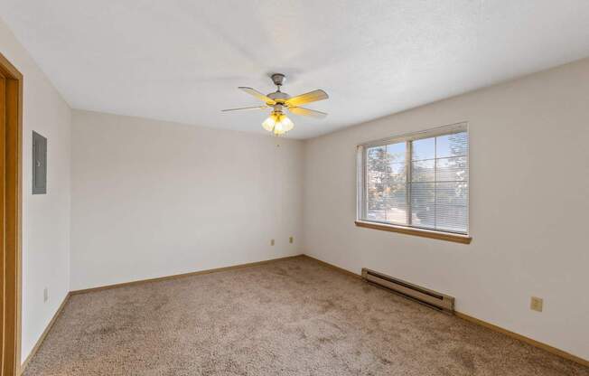 an empty living room with a ceiling fan and a window