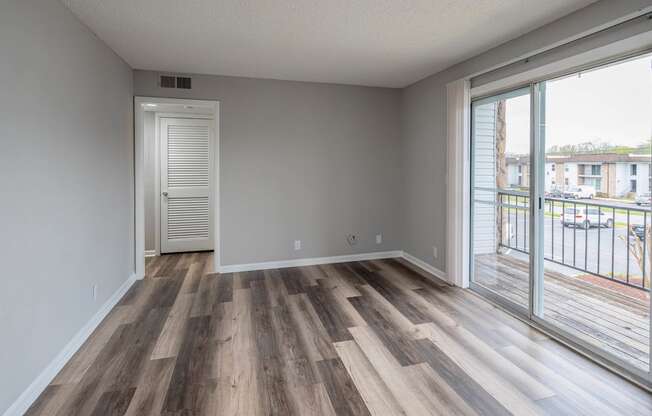 a bedroom with hardwood flooring and a sliding glass door leading to a balcony