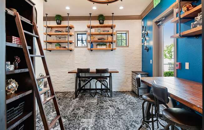 Coworking nook with bar-height desks, floating shelves, and library ladder accent wall.