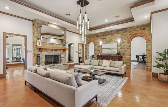 A large, modern resident lounge with a stone fireplace and a long beige sofa at Creekside on Parmer Lane Apartments in Austin, TX