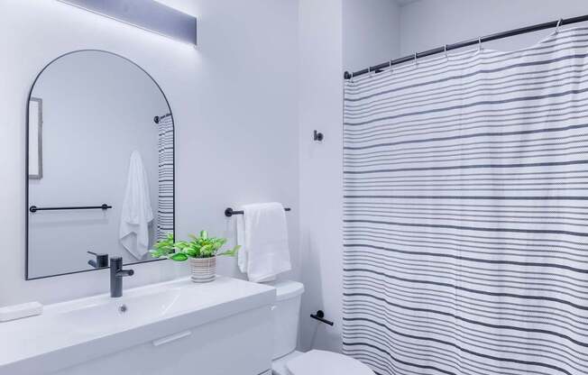 A white bathroom with a toilet, sink, and a shower curtain.