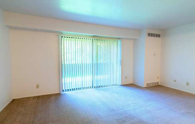 an empty living room with a large window and carpeting