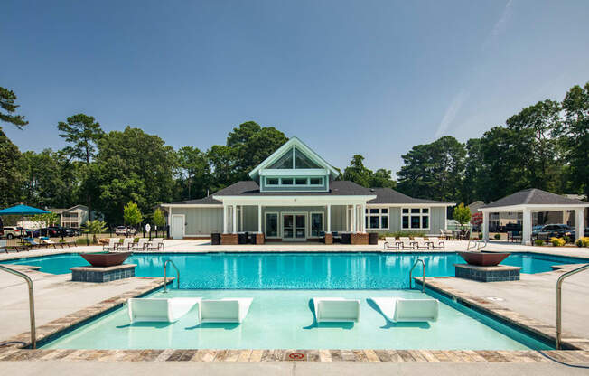 a swimming pool with lounge chairs and a club house in the background