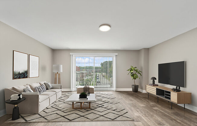 Model Living Room with Wood-Style Flooring and Patio Accessibility at Heights at Marlborough Apartments located in Marlborough, MA.