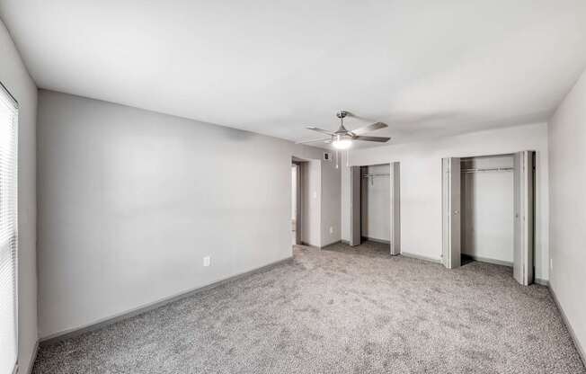A room with a ceiling fan and carpeted floor.