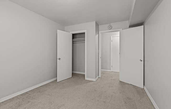 A room with carpeted floors and three doors.