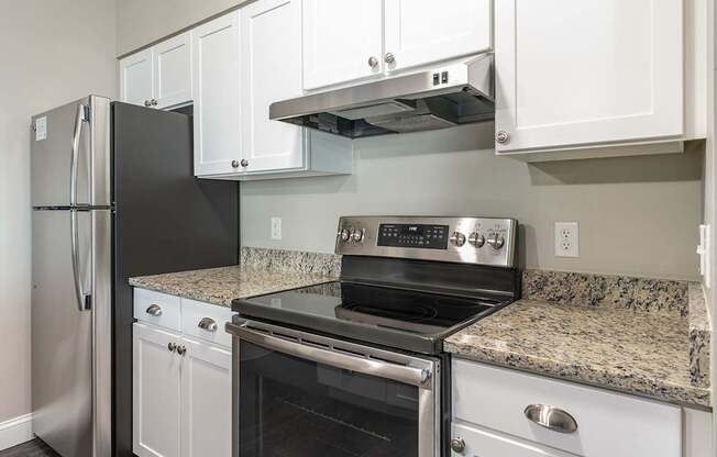 Parkside Commons apartment kitchen with refrigerator next to a black stove in a kitchen.