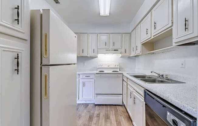 an empty kitchen with white cabinets and white appliances