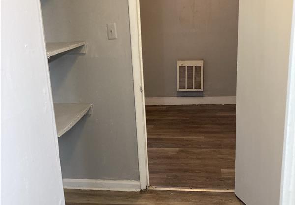 A room with a white door and a wood floor.