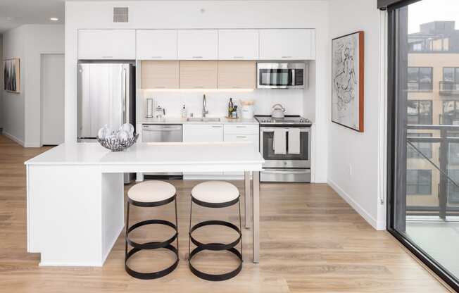 a kitchen with white cabinets and a white island with three stools