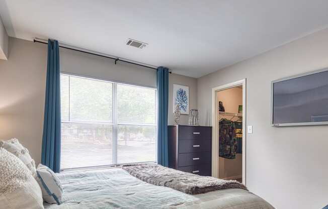 a bedroom with a large window and a bed with blue curtains