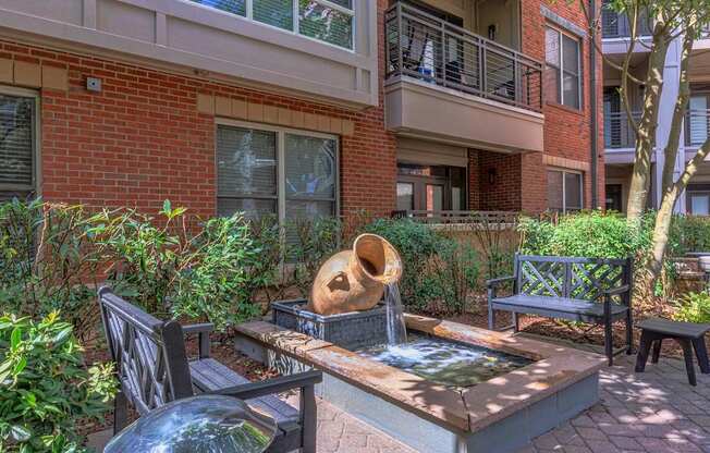 A patio with a fountain and chairs.
