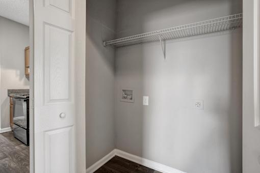 A white door is open to a room with a white wall and a white shelf.