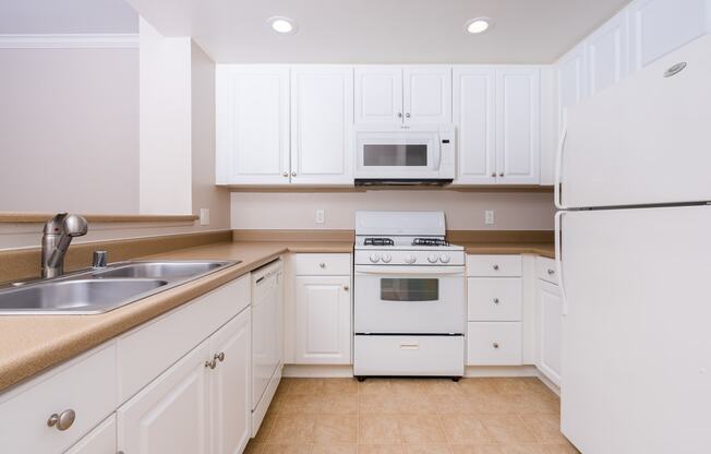 a kitchen with white cabinets and white appliances