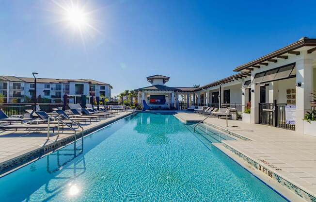 A sunny day at the pool with chairs and buildings in the background.