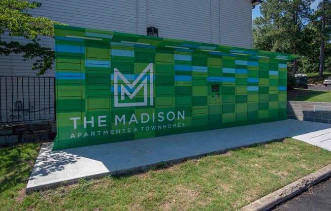 A green and blue sign for The Madison Apartments & Townhomes.