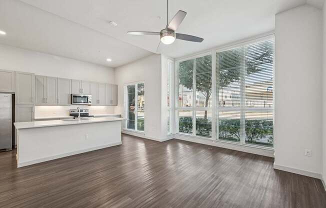 A spacious kitchen with a fan and wooden flooring.