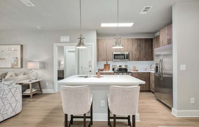 A modern kitchen with a white island and two chairs at The Ashton at East Park Apartments, Kennesaw, GA