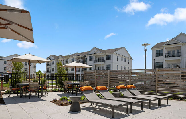 A patio with chairs and umbrellas in front of apartment buildings at Madison Prickett Preserve, Yardley