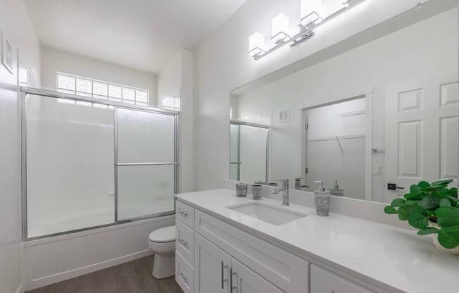 A white bathroom with a toilet, sink, and mirror.