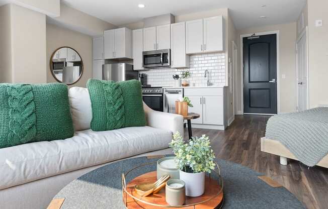 a living area with a couch coffee table and a kitchen in the background