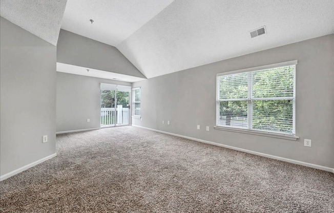 an empty living room with a large window and carpet