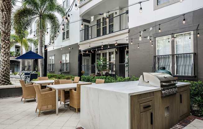 A patio with a table, chairs, and a grill.