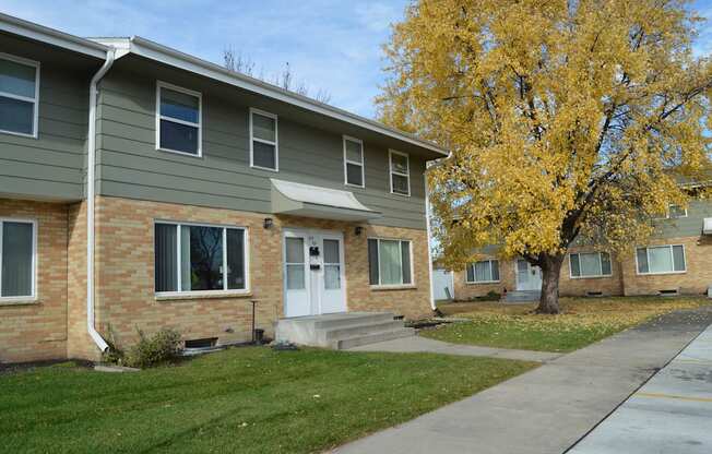 an apartment building with a sidewalk and a tree. Fargo, ND Sheyenne Terrace