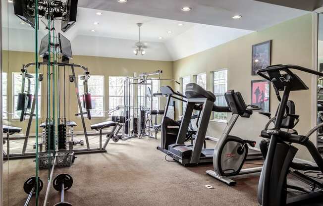 Fitness Center with exercise equipment, three windows on each of the two walls and a mirror accent wall.