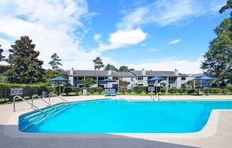 A swimming pool surrounded by trees and a building in the background.