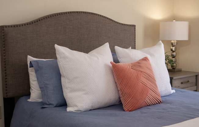 a bed with blue sheets and pillows and a brown headboard