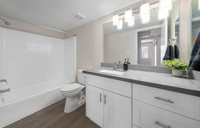 A white bathroom with a toilet, sink, and mirror.