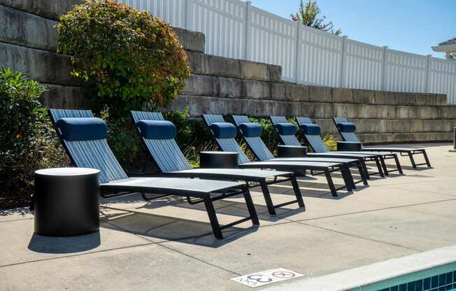 a row of lounge chairs and tables next to a pool
