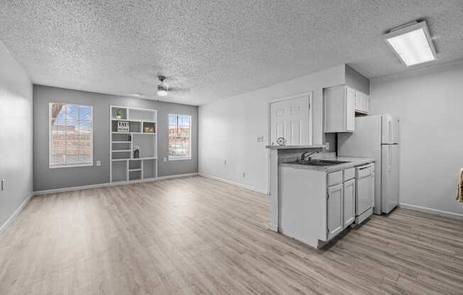 the living room and kitchen of an apartment with white appliances and wood floors
