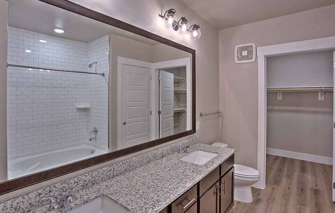 a bathroom with a sink and a large mirror at Hunters Creek Apartments, Denton, TX
