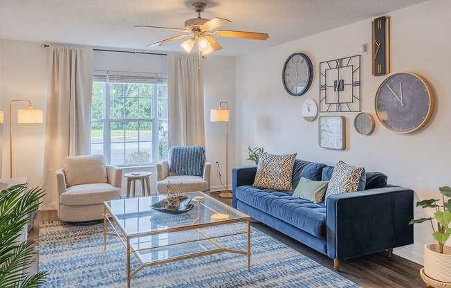 A living room with a blue couch and a glass coffee table.