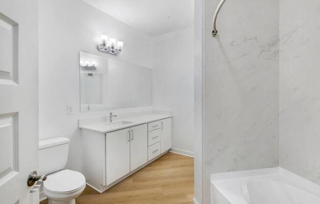 A white bathroom with a toilet, sink, and bathtub.