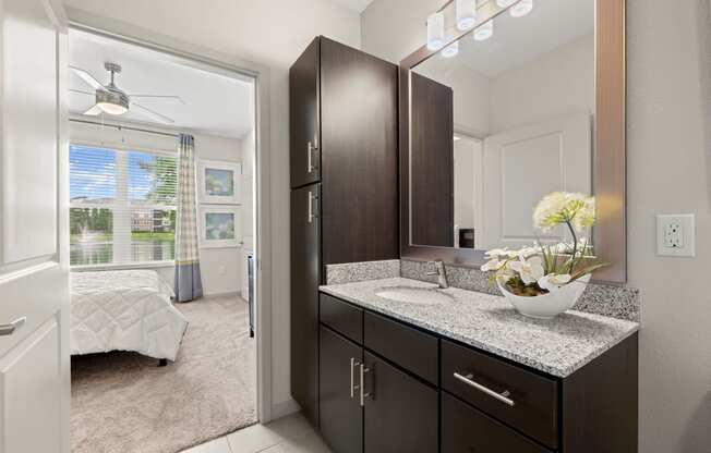 a bathroom with dark cabinets and a vanity with a sink