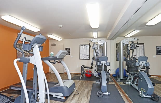 a gym with exercise equipment and a bulletin board on the wall