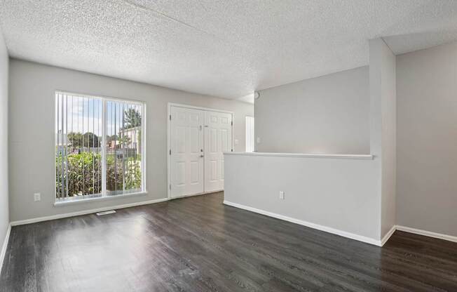 A spacious room with a view of a fence and trees through the window.