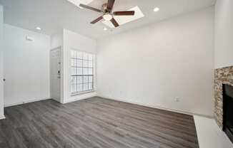 an empty living room with a ceiling fan and a fireplace