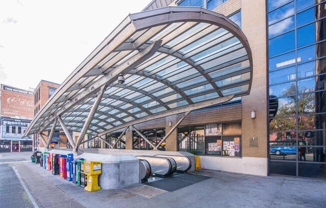 A row of colorful trash cans are lined up outside a building.