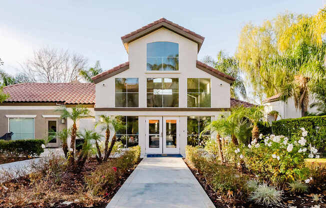 A house with a red tile roof and a white exterior with a glass door and windows.