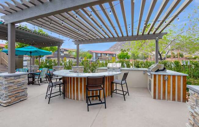A patio with a table and chairs under a wooden pergola.