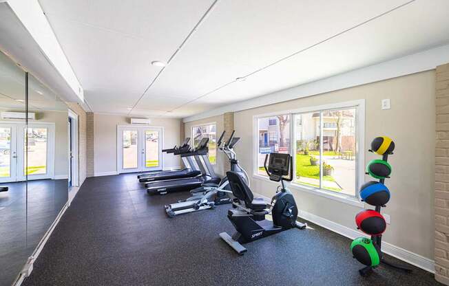 A gym with treadmills, elliptical machines, and a row of exercise balls.