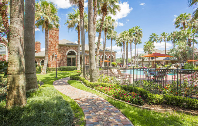 a pathway leading to a swimming pool with palm trees