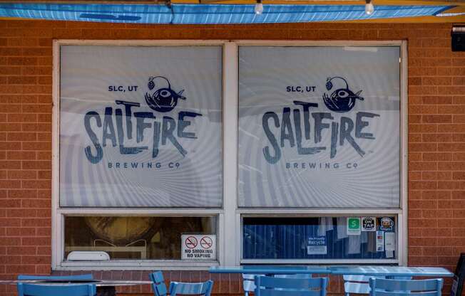Saltfire Brewing Co. logo on a window with blue chairs outside.
