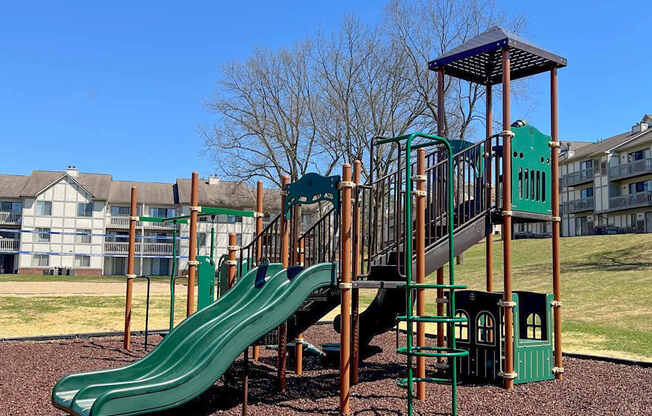 A playground with a green slide and a wooden structure.